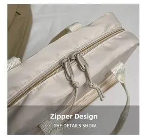 Close-up of the smooth dual zipper design with drawstring pulls on the cream beige bag
