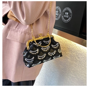 Detail of a vintage black clutch with silver sequins and a gold chain strap on a shoulder