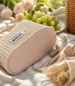 Detail of woven straw handbag base with pink faux leather trim and ribbon bow accent