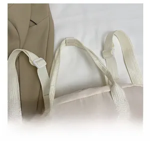 Detail of cream casual tote bag showing woven top handle and adjustable strap buckle