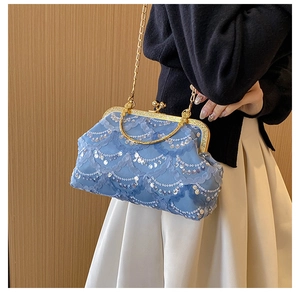 Close-up of light blue lace evening bag with silver sequins and golden metal handle