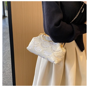 Detailed shot of white lace sequin clutch bag with golden metal frame and chain strap