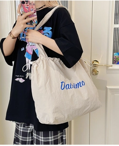 Detail of cream canvas tote bag featuring Davimo logo and adjustable drawstring closure