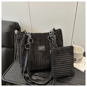 Close-up of black corduroy tote bag texture with silver chain and matching small pouch
