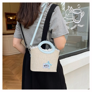 Detail view of woven straw bucket bag featuring blue leather trim and delicate lace edges
