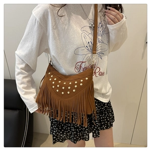 Detail van bruine mat leren crossbodytas met gouden noppen en lange franje kwastjes