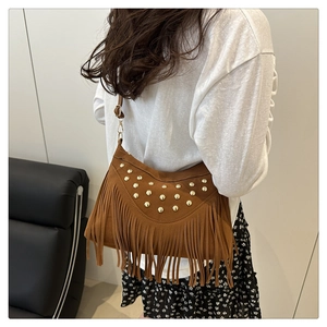 Detailed view of bohemian brown suede fringe bag with gold rivets on shoulder