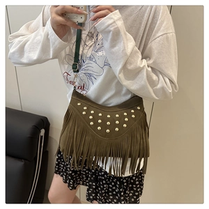 Detail van olijfgroene suède crossbodytas met franjes en goudkleurige noppenaccenten