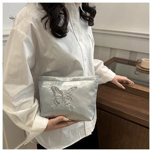 Detail of silver-blue satin clutch with butterfly embroidery and zipper closure