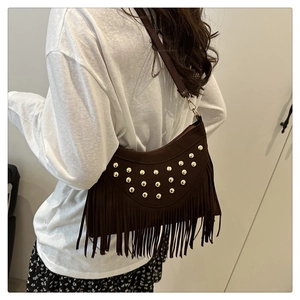 Detail view of brown faux suede shoulder bag with gold studs and long tassel fringe