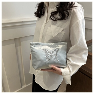 Detail of light blue satin makeup bag featuring a delicate butterfly embroidery pattern
