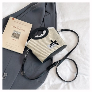 Detailopname van beige strooien tas met zwarte lederen handvatten en witte kanten rand