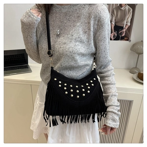 Modieuze zwarte crossbody tas met gouden klinknagels en lange franjes getoond op model