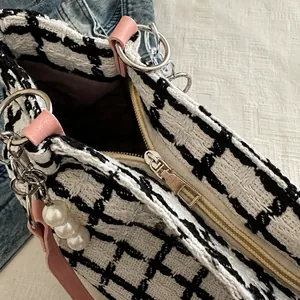 Detail of houndstooth tote with silver zipper, pink leather loops and pearl charms