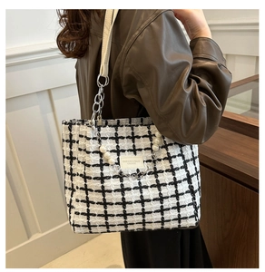 Detail of tweed checkered tote bag featuring pearl chain strap and leather fashion label