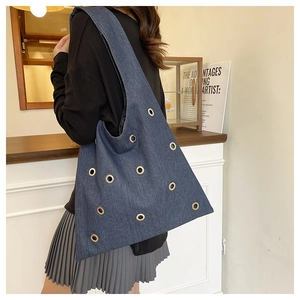 Détail du sac hobo en jean bleu avec plusieurs œillets décoratifs en métal doré