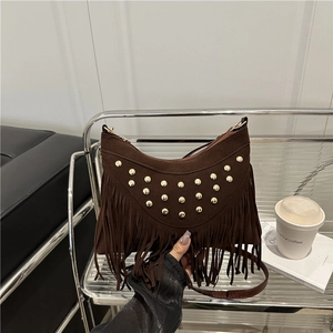Retro dark brown suede crescent bag with metal rivets and long tassels on a studio rack