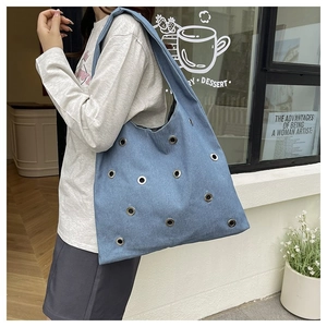 Détail du sac cabas en jean bleu avec œillets métalliques pour le trajet quotidien