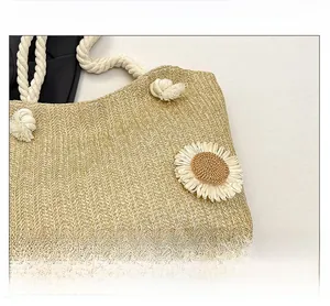 Dettaglio della borsa in paglia intrecciata con margherite bianche e manici in corda di cotone