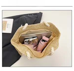 Vista dall'alto della borsa in paglia intrecciata con grande capacità per laptop e accessori