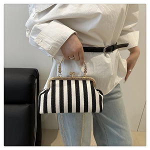 Détail du sac coquille à rayures noires et blanches avec poignée dorée et chaînette