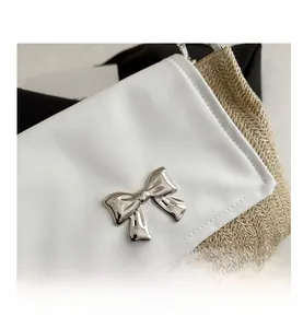 Detail of white leather flap with silver metal bow clasp on a woven straw handbag