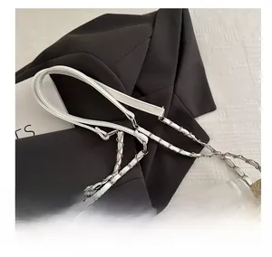 Close-up of a white leather and silver metal chain strap on a woven crossbody bag