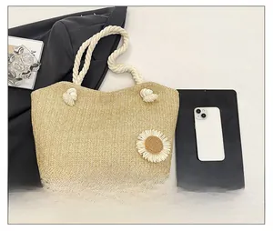 Dettaglio borsa tote in paglia intrecciata marrone chiaro con margherita e corda