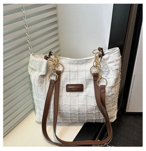 Detailopname van witte tweed shopper met geweven textuur, bruin leer en gouden ketting