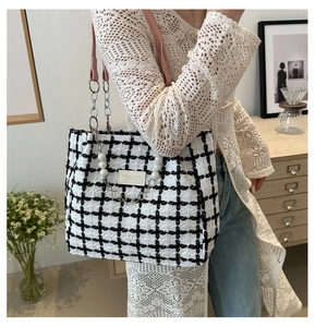 Detail of checkered tote bag with pink strap, silver chain, and pearl charm decoration