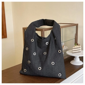 Détail du sac cabas en denim gris foncé avec œillets métalliques argentés et larges anses