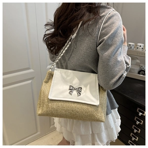 Detailed view of the silver bow clasp and woven straw texture on the shoulder bag