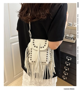 Detail der weißen Umhängetasche aus Leder mit Boho-Fransen und metallischen Nieten