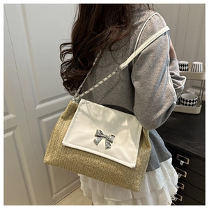 Detail showing straw woven texture and white leather flap with silver bow clasp on bag