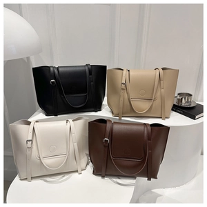 Detail view of large minimalist tote bags in neutral colors displayed on modern platforms