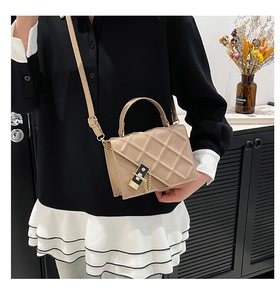 Borsa a tracolla beige trapuntata con catena indossata da una modella in casa