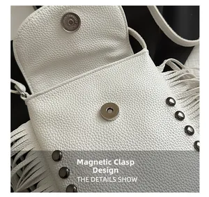 Detail of white lychee leather bag featuring tassel fringe, metal rivets, and magnetic closure