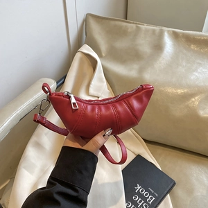 Chic red pleated croissant bag with silver zipper and detachable strap shown in a hand
