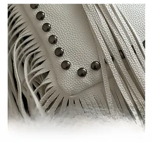 Detail showing white lychee grain leather texture with fringe tassels and metal studs