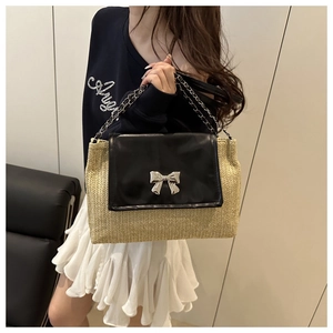 Straw shoulder bag with black leather flap, silver bow clasp, and chain strap detail
