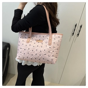 Detail der rosa Tasche mit Schleifenmuster, Plissee-Textur und goldener Plakette