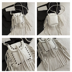 Detail view of white crossbody phone bag featuring long leather tassels and silver metal studs