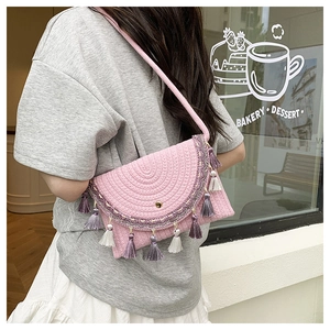 Detail of pink woven crossbody bag featuring bohemian purple tassels and ethnic embroidery