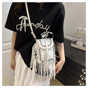 Close-up of white tassel crossbody bag with rivet details and litchi grain texture