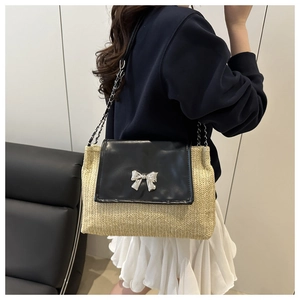 Detail of straw woven texture and black leather flap with silver bow metal clasp