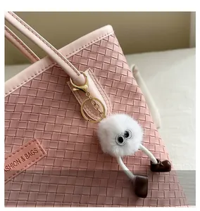 Détail d'un pendentif monstre blanc en peluche avec de grands yeux sur un sac rose
