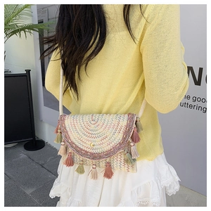 Detail of woven straw bag with multi-color wave embroidery and tassel accents