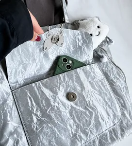 Close-up of the front magnetic pocket with butterfly charm on silver tote bag