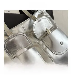 Detail of silver metallic tote bag featuring double pockets with magnetic buckle closure