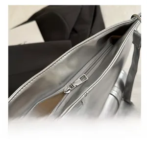 Close-up of smooth silver zipper and light brown fabric lining on a metallic tote bag